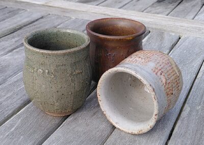 Trio de tasses à café facettées. L'un est en céladon, le deuxième est rouge et le troisième shino