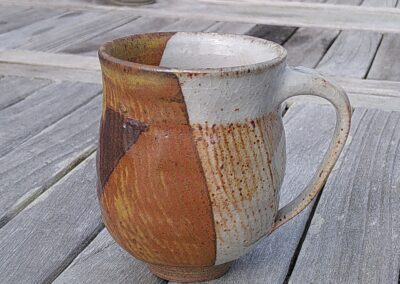 Mug facetté avec anse de couleur shino et rouge.